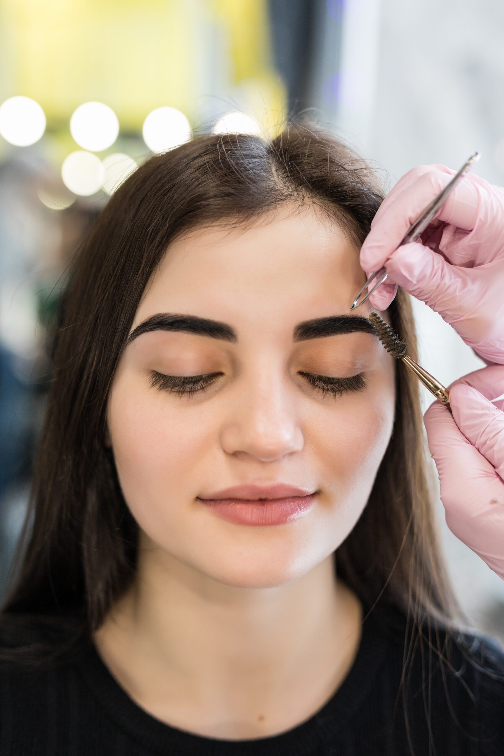 master doing final steps in make-up procedure for model with green eyes